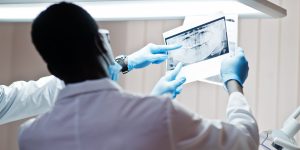 Dentist office and doctor practice concept. Professional african american doctor at dentistry medical pointing on teeth X-ray.